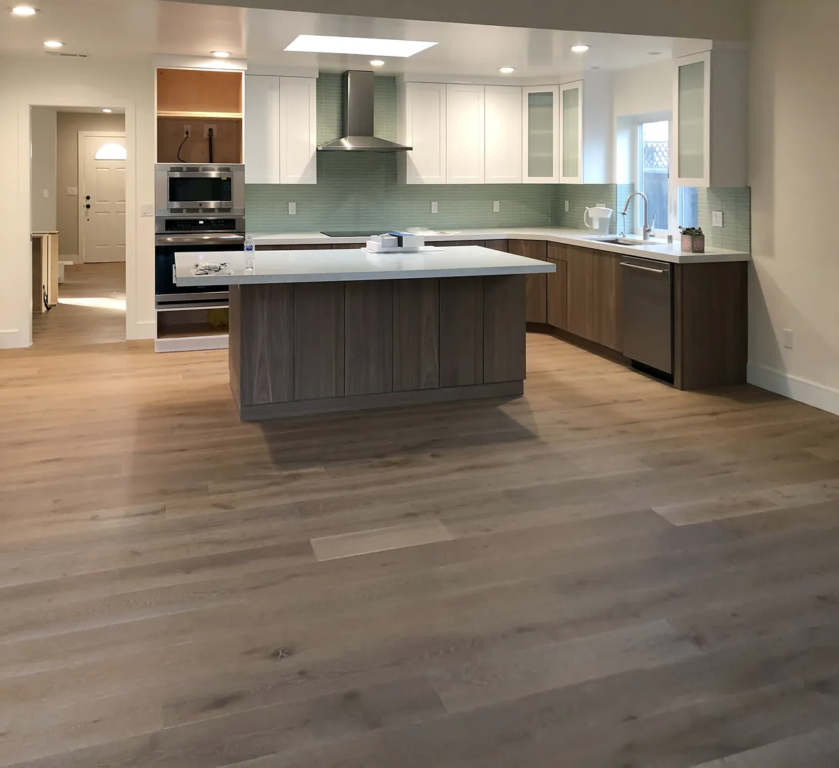 Open kitchen with walnut lower cabinets, white uppers, a glass-tile backsplash and an island